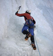 Eiskletterer mit Eispickel und Steigeisen in einer Eiswand