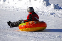 Kind rutscht auf einem bunten Snowtube auf Schnee