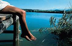 Frau entspannt auf einem Steg am See